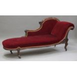 A Victorian mahogany chaise longue, carved with leaf and flower decoration, upholstered in red
