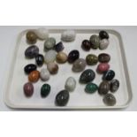 A collection of polished hardstone specimen eggs, contained within a wooden box.Buyer’s Premium 29.