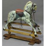 An early 20th century carved and painted wooden rocking horse, raised on a pine stand, bearing