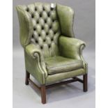 A 20th century George III style green leather wing back armchair, raised on moulded block legs,