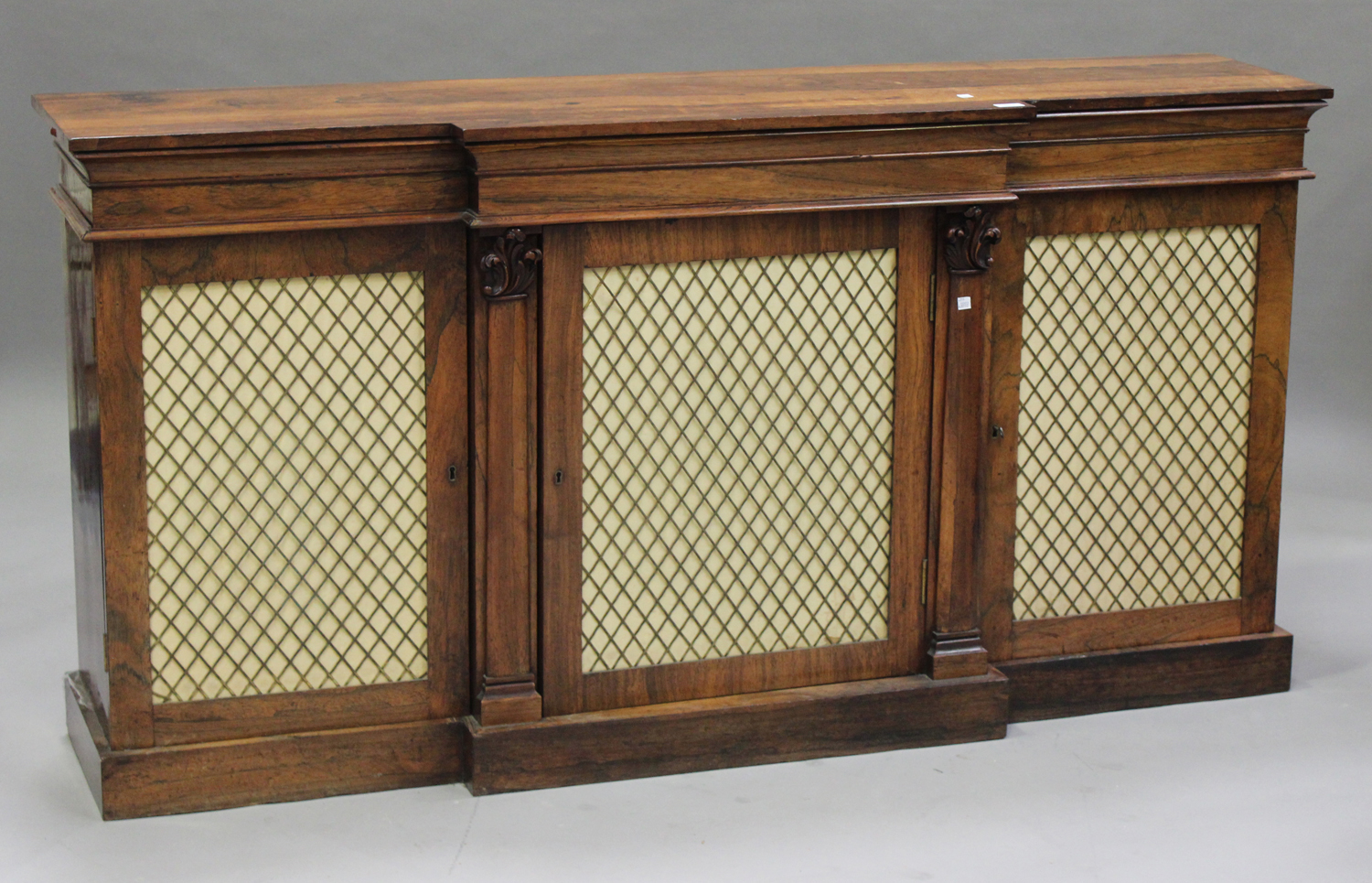 A Regency rosewood breakfront cabinet, the top with a moulded edge above cupboards enclosed by three