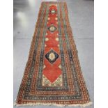 A West Persian runner, early 20th century, the red field with three blue medallions, within a