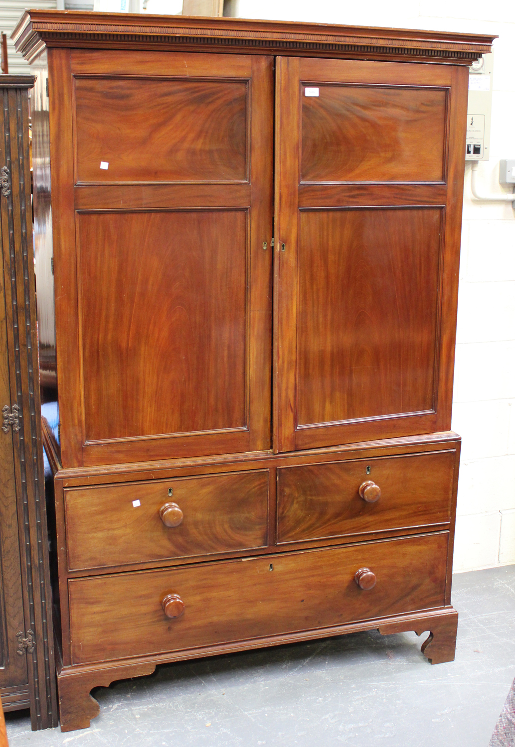 A Victorian figured mahogany linen press, the dentil moulded pediment above a pair of panel doors