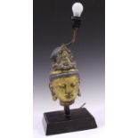 A South-east Asian gilt cast composition head of a female deity, mounted as a table lamp, height