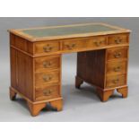 A 20th century reproduction yew twin pedestal desk, fitted with an arrangement of drawers, on