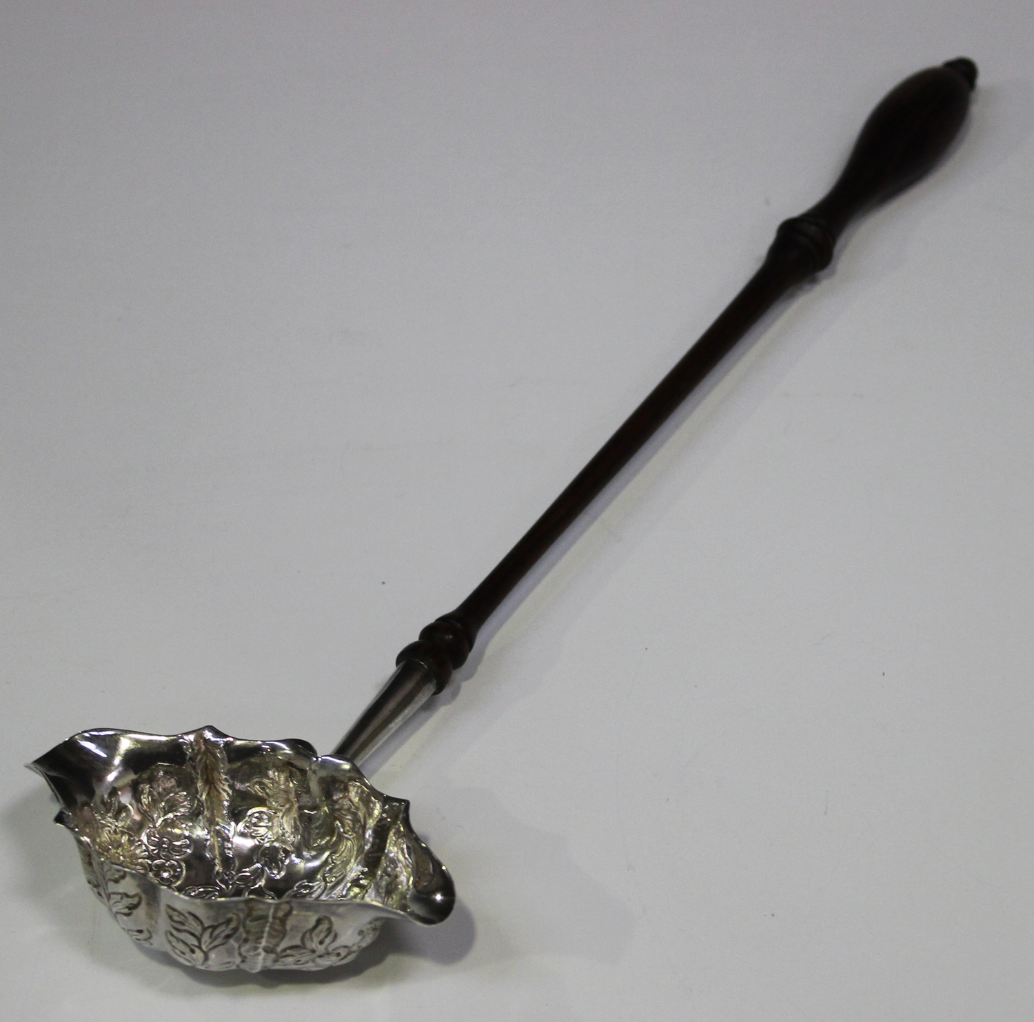 A George III silver punch ladle, the oval shaped bowl decorated with leaves and flowers, with a