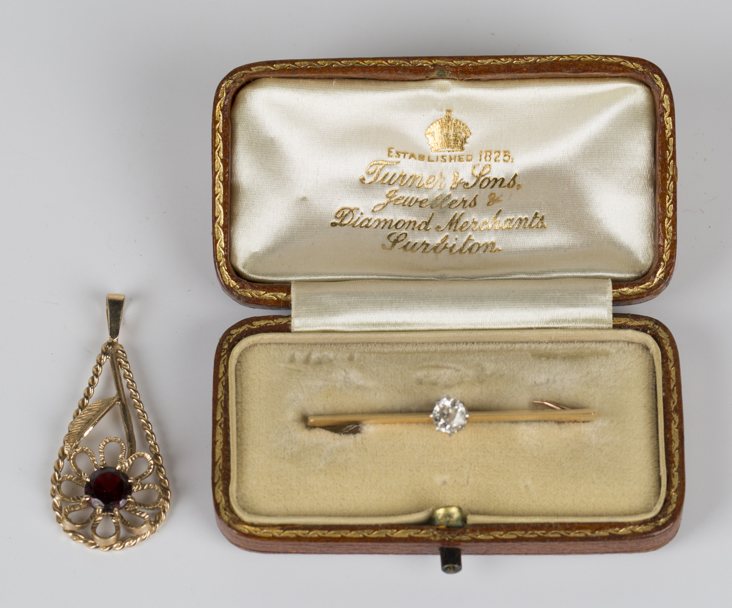 A gold and diamond single stone bar brooch, claw set with a cushion shaped diamond on a knife edge