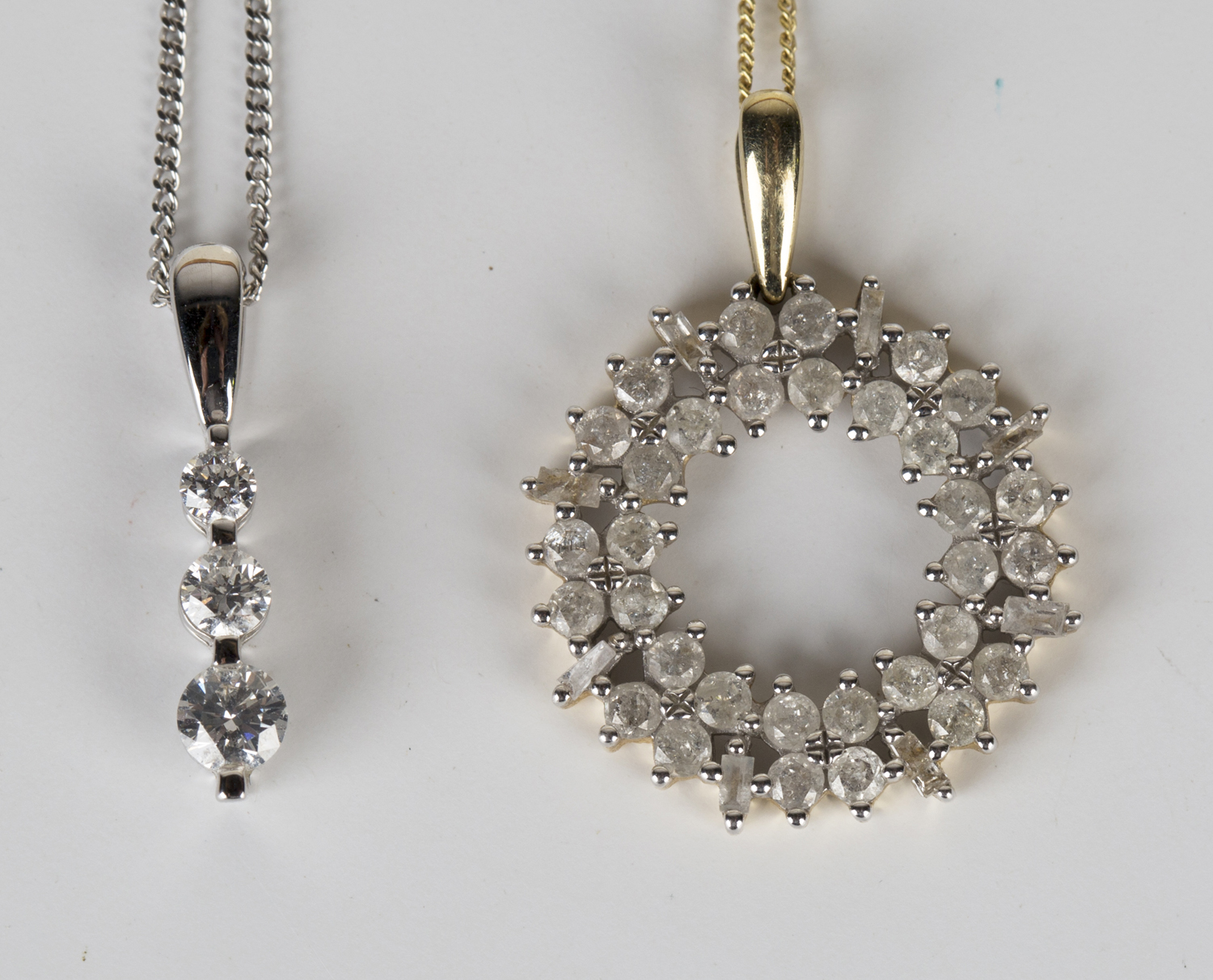 A white gold and diamond three stone pendant, claw set with a row of graduated circular cut