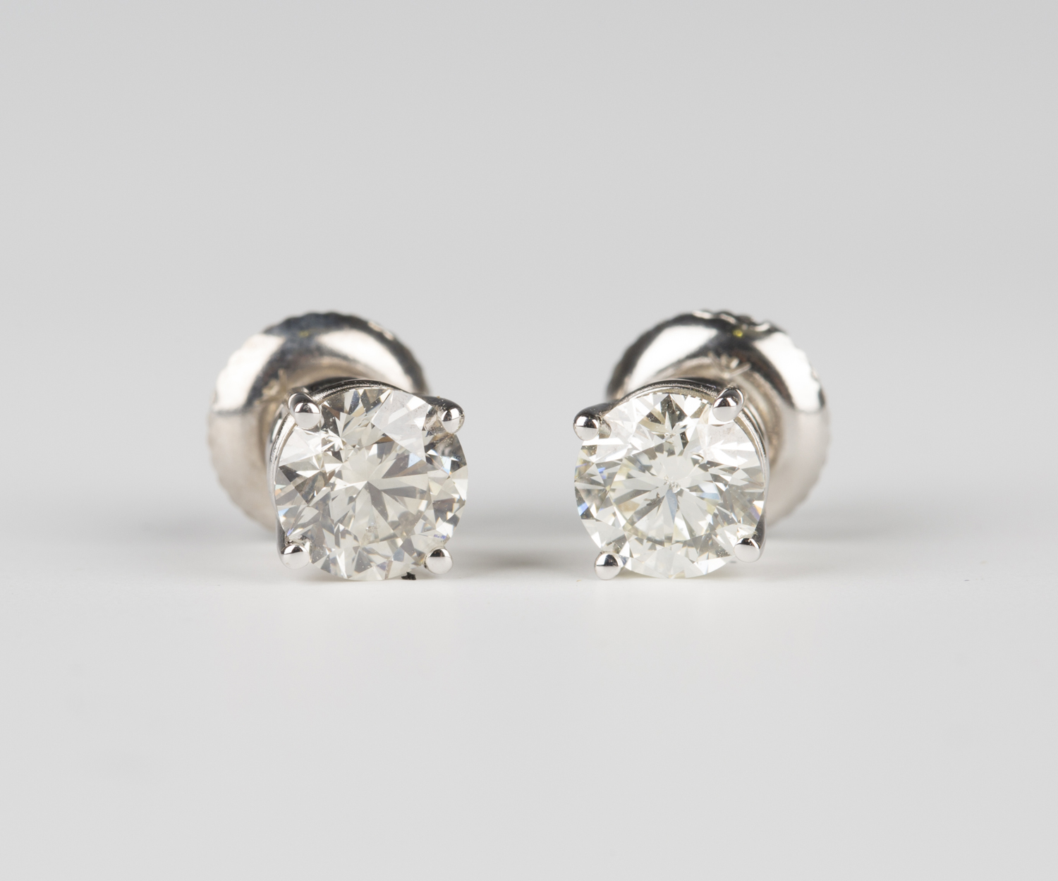 A pair of white gold and diamond single stone earrings, each claw set with a circular cut diamond,