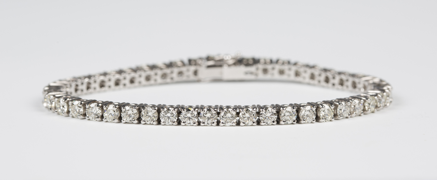 A white gold and diamond bracelet, claw set with a row of circular cut diamonds, on a snap clasp,