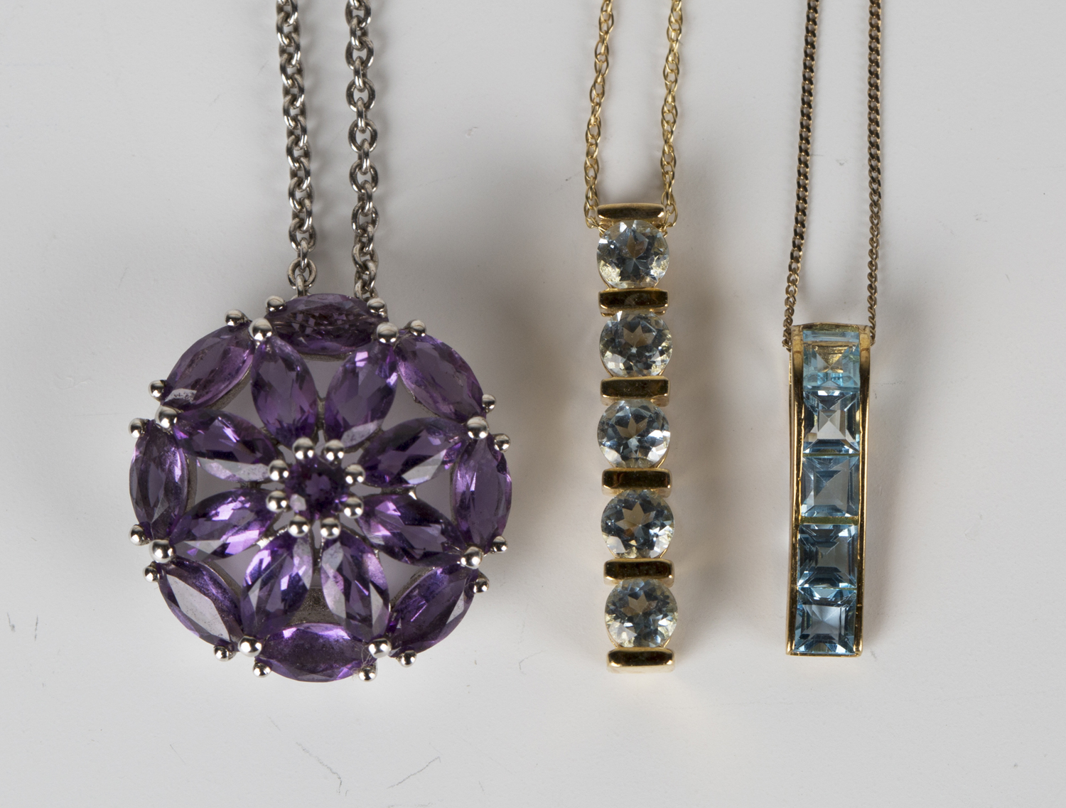 Two 9ct gold and pale blue gem set pendants with 9ct gold neckchains, and a silver and amethyst