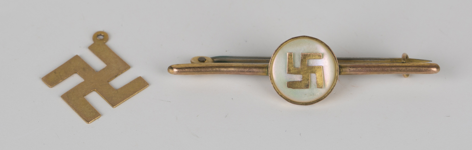 A gold and mother-of-pearl bar brooch, the circular mother-of-pearl centre mounted with a fylfot