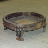 A 19c African milling table of circular form with raised border, carved and supported on four