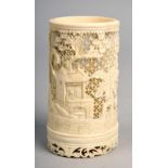 A Japanese carved ivory cylindrical pot, pierced and carved with village scenes, 4in h.