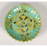 A tin glazed lobed dish of blue/green ground painted with yellow and black stylised flowers, 9.