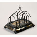 A 19c toleware letter rack, black lacquered and gilt decorated with flowers and insects, supported