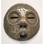 A 19c African coastal region carved wood mask, decorated with shells, 11.5in diam.