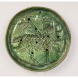 A Medieval pottery circular plaque, green glazed, pierced and moulded with the Lamb of God and