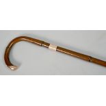 A stained bamboo walking cane with gold band and handle terminal, 39in l.