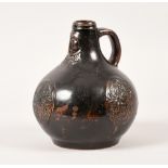 A 17c dark brown glazed Bellarmine jug with mask and three cartouches, 9in h.