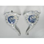 A pair of blue and white pottery cornucopia wall pockets with transfer printed scene of cherubs with