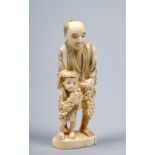 A Japanese carved figure group of a gentleman accompanied by a child both carrying bunches of fruit,