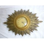 An electric wall clock with circular dial in gilt sunburst case