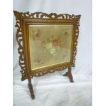 A Victorian rosewood rectangular fire screen with pierced decoration and inset needlework floral