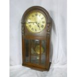 A 1930's wall clock with silvered circular dial in polished carved oak domed case