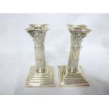 A pair of Edward VII silver Corinthian column candlesticks with fluted stems and square stepped