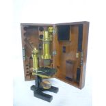 An old brass and painted metal monocular microscope by Baker of London in fitted mahogany case with