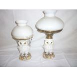 Two German china oil lamps in the form of owls standing on rocky bases,