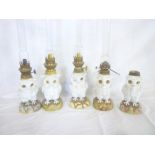 Five small Continental china oil lamps in the form of owls on rocky bases with brass mounts