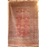 An Eastern hand-knotted wool rug with geometric decoration on red ground 73" x 47" (af)
