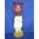A large German china oil lamp in the form of an owl standing on an encrusted floral base with brass