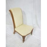 A Victorian walnut nursing-style occasional chair upholstered in cream fabric on turned legs with