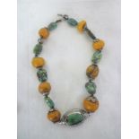 A Middle-Eastern silvered necklace mounted with amber and turquoise