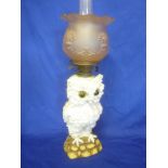 An unusual German china oil lamp in the form of an owl on a rocky base with brass mounts and pink
