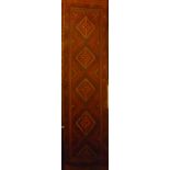 An Eastern hand knotted wool runner with geometric decoration on red ground 100" x 24"