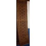 An Eastern hand knotted wool runner with geometric decoration on red and green ground 100" x 24"