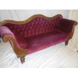 A Victorian mahogany double scroll end sofa upholstered in red buttoned fabric on turned tapered