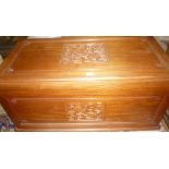 An Eastern rectangular carved Camphor wood trunk with decorated panels and hinged lid with