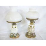 Two various small china oil lamps in the form of owls on floral encrusted bases,
