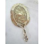An ornate silver hand mirror decorated in relief with various dragons and bamboo mounts