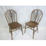 A set of four beech and elm wheel-back dining chairs with shaped seats on turned tapered legs (af)