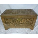 An old Eastern carved camphor wood rectangular trunk decorated all-over with figures and landscapes