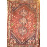 An Eastern hand-knotted wool rug with geometric decoration on red ground 98" x 68"