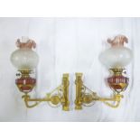 A pair of Victorian gilt brass oil lamp wall brackets with angled decoration supporting a pair of