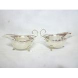 A pair of George V silver classical-shaped sauce boats with scroll handles on hoof feet,