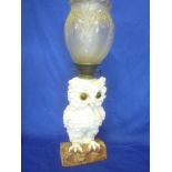 An unusual German china oil lamp in the form of an owl perched on a branch with glass eyes,